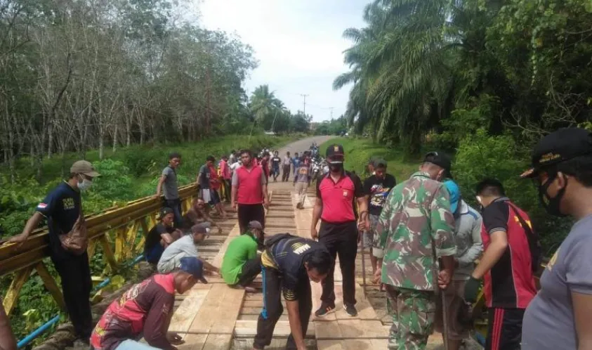 Personil Kepolisian Sektor Giri Mulya Bantu Warga Perbaiki Jembatan Penghubung Desa
